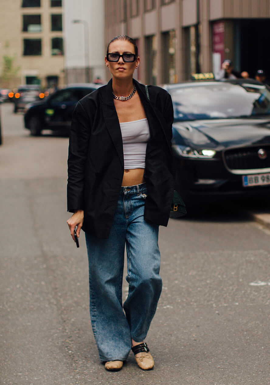 Frau trägt ein lässiges Outfit und kombiniert zu einem schwazen Blazer eine lockere Jeans