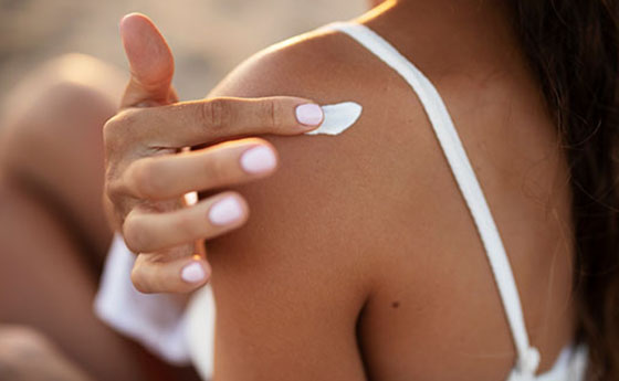 Frau cremt sich ihre Haut mit Sonnenschutz ein