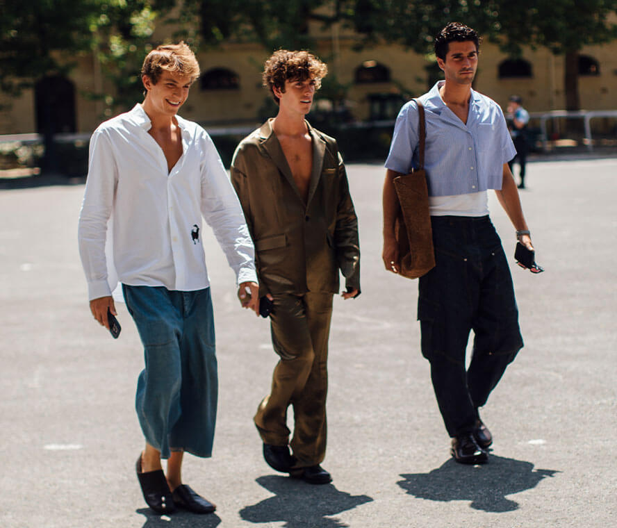 Drei Männer laufen nebeneinander und tragen legere Outfits im Casual Dresscode