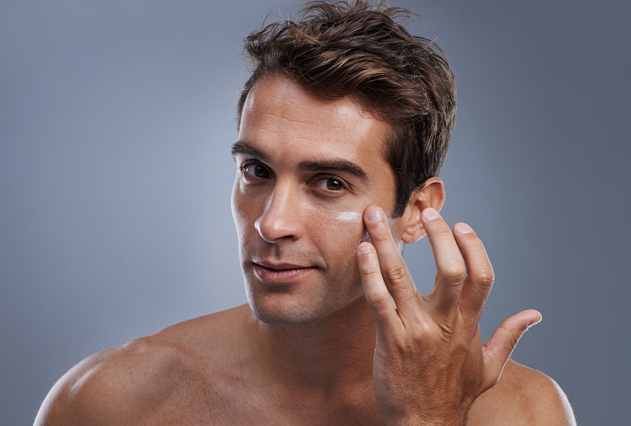 Mann pflegt die Haut unter den Augen mit einer Augenpflege