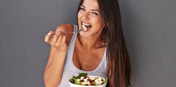 Frau isst Salat für gesunde Haut