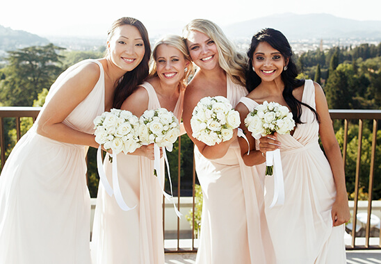 Brautjungfern in hellen Kleidern mit Blumensträussen