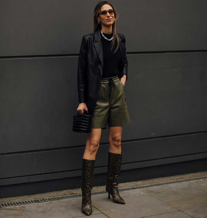 Frau trägt im Sommer 2024 kurze grüne Ledershorts zum schwarzen Lederblazer