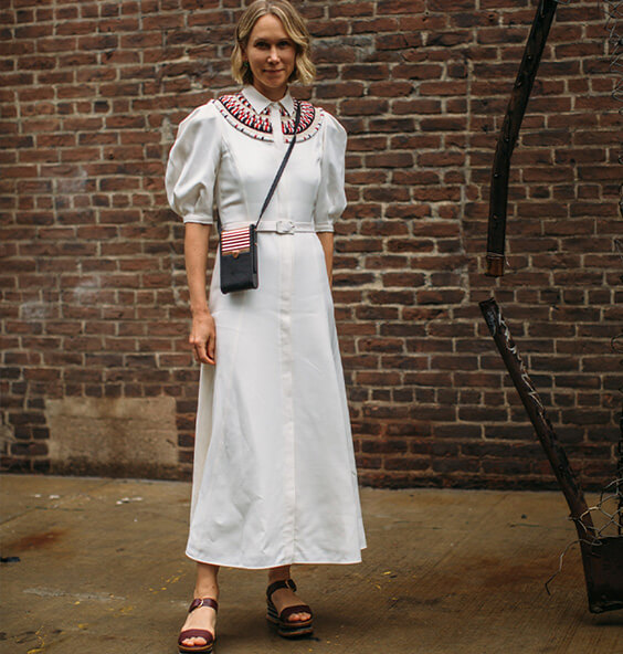 Frau trägt im Sommer 2024 Plateausandalen zu einem weissen Sommerkleid mit Ethno-Stickerei