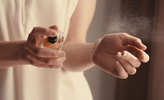 Frau sprüht sich Parfum an ihr Handgelenk