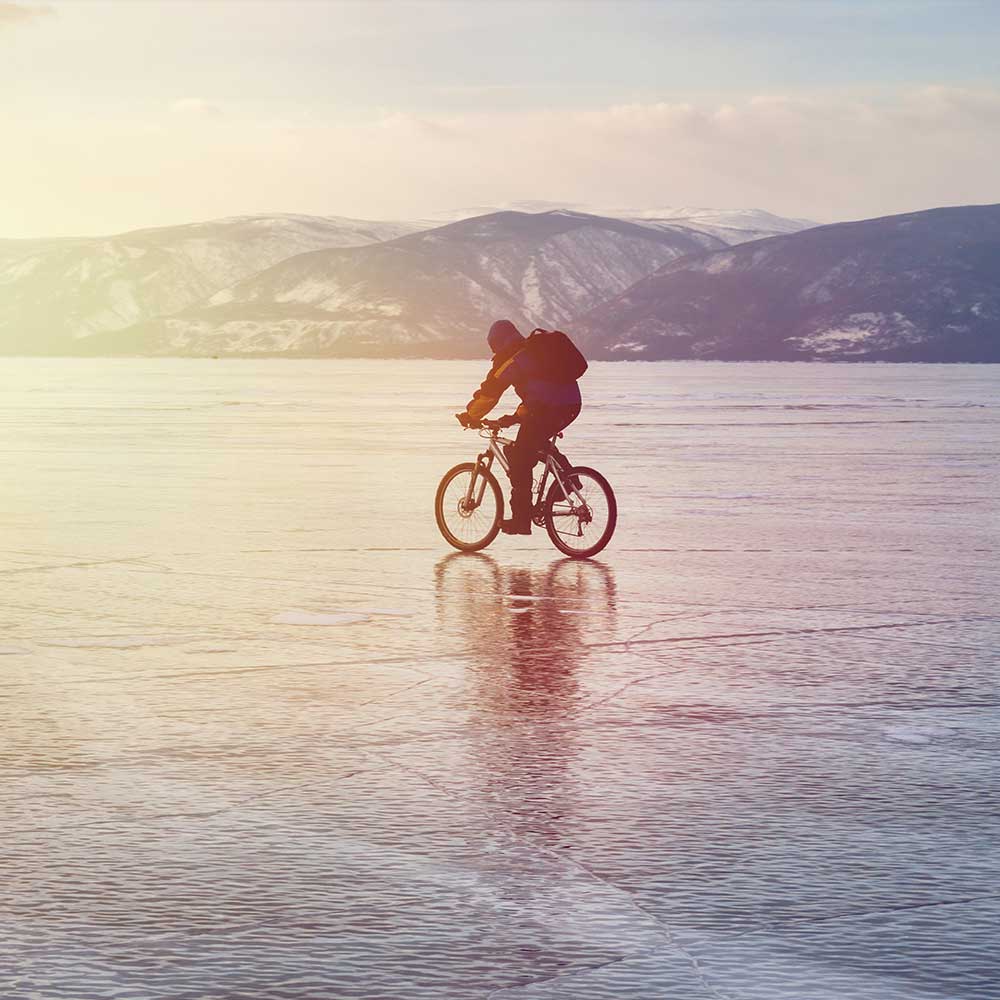 Mann fährt mit seinem Fahrrad über einen zugefrorenen See