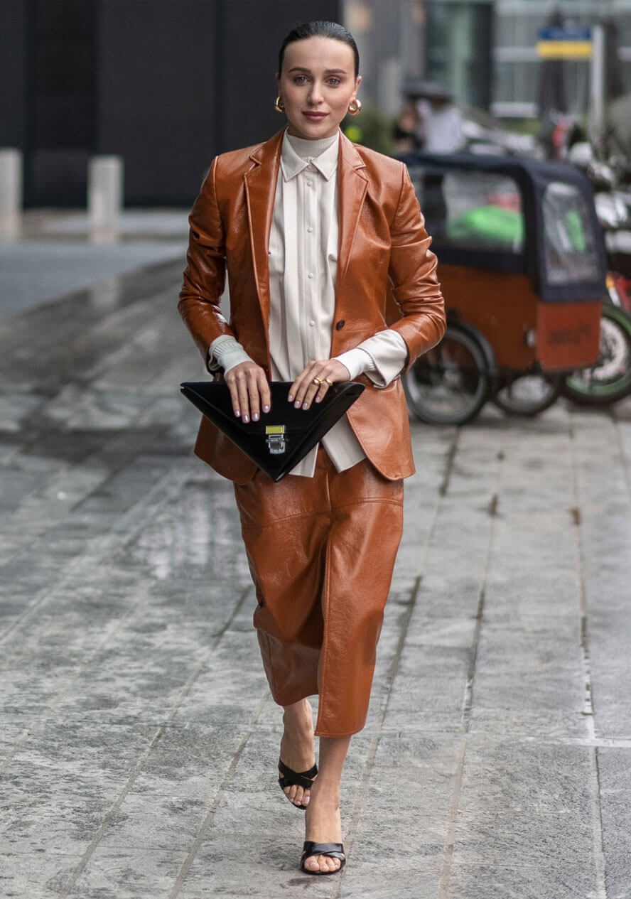 Frau trägt eine braune Business-Kombination und kombiniert zu einer cognacfarbenen Lederhose einen Blazer