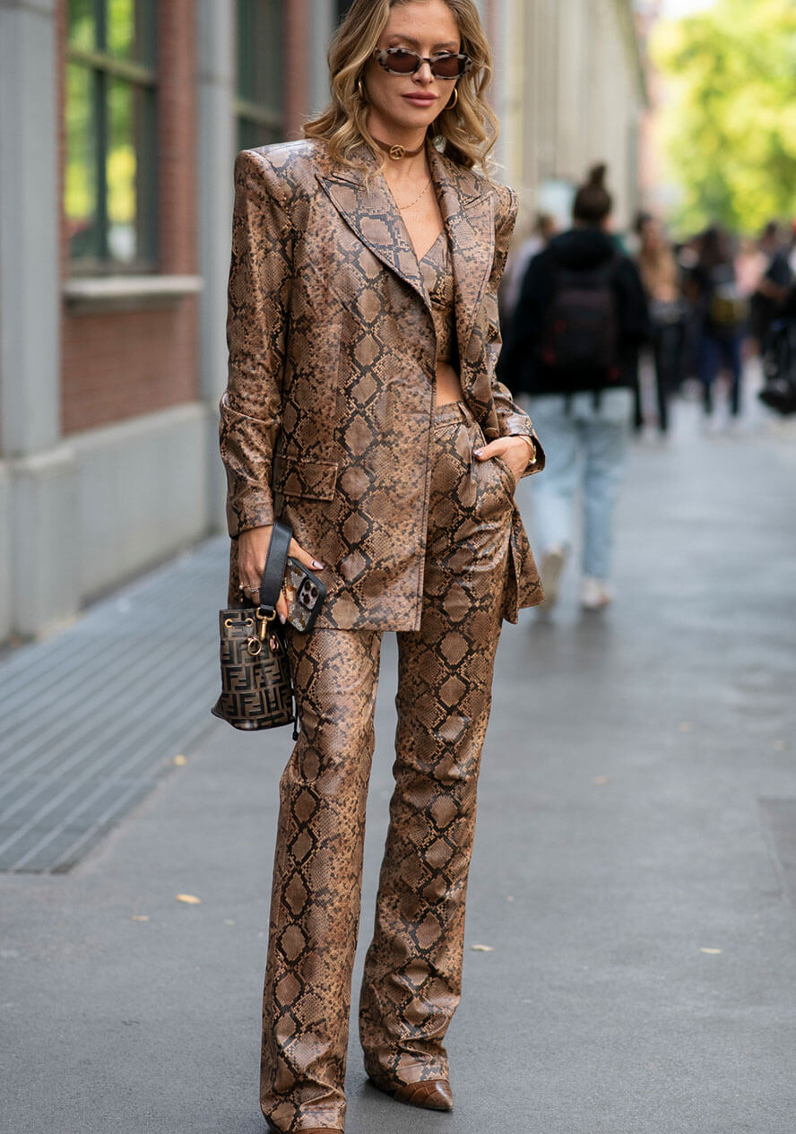 Frau trägt einen all-over Animal Print Look mit einer Lederhose und Blazer im Schlangenmuster