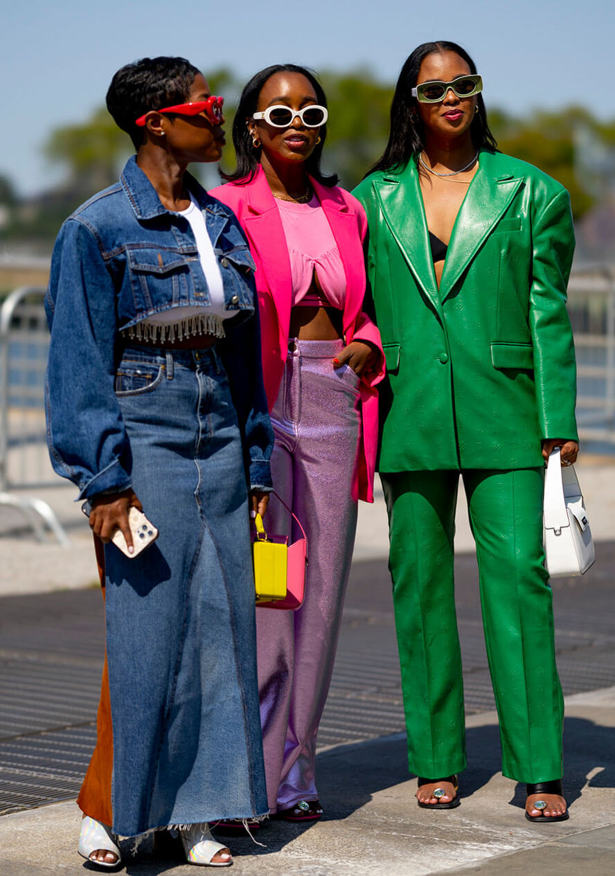 Drei Frauen in bunten Outfits aus Denim, in rosa und in grünem Leder