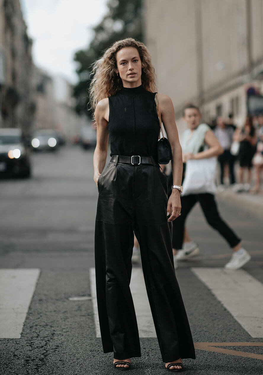 Frau trägt eine schwarze Lederhose kombiniert mit einem schwarzen Top als schlichten Business Look