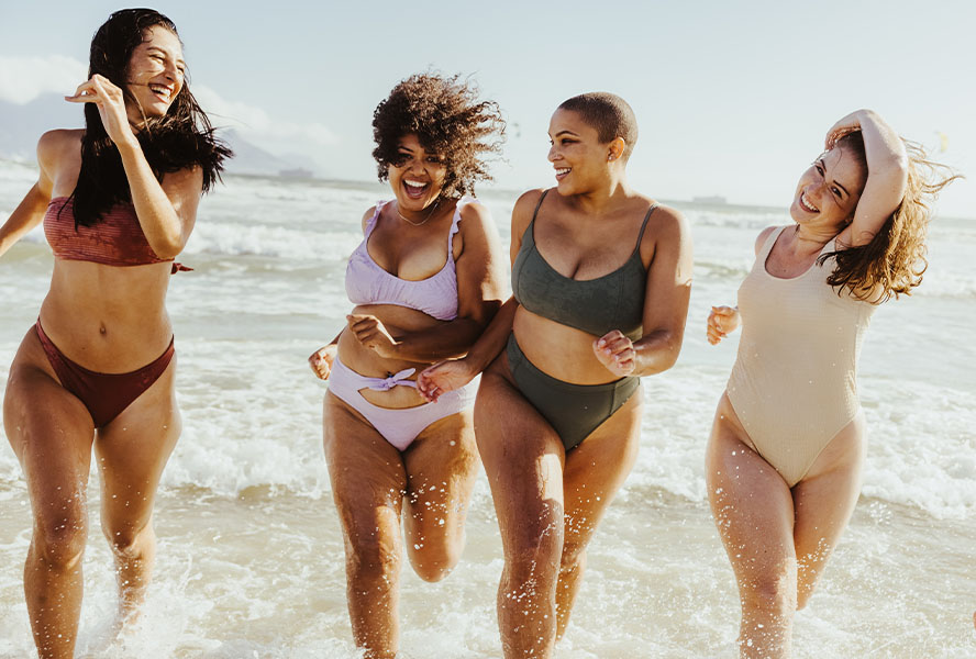 Gruppe Frauen am Strand in Bikinis und Badeanzügen