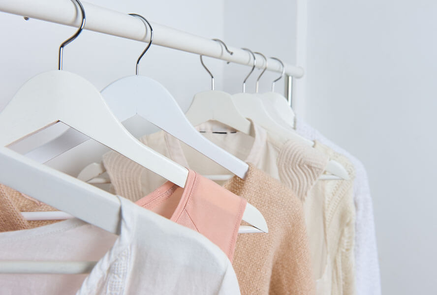 Verschiedene Damen Kleidungsstücke auf einer Kleiderstange: Pullover, T-Shirt, Bluse