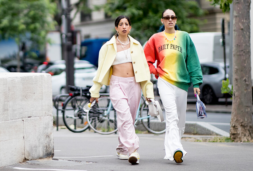 Zwei Frauen in bunten Y2K-Looks aus Baggy Hosen und weiten Oberteilen