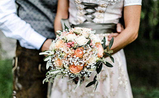 Frau im Hochzeits-Dirndl mit Blumenstrauß