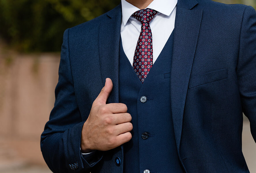 Mann im dunkelblauen Sakko und einer roten, gemusterten Krawatte