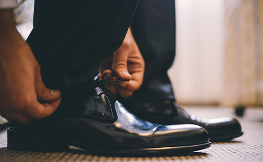 Mann bindet sich schicke schwarze Schnürer für einen Black Tie Look