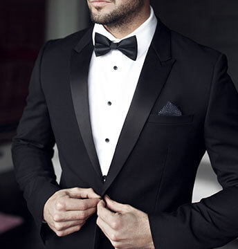 Mann in einem schicken Black Tie Outfit trägt einen Smoking mit Fliege und Einstecktuch