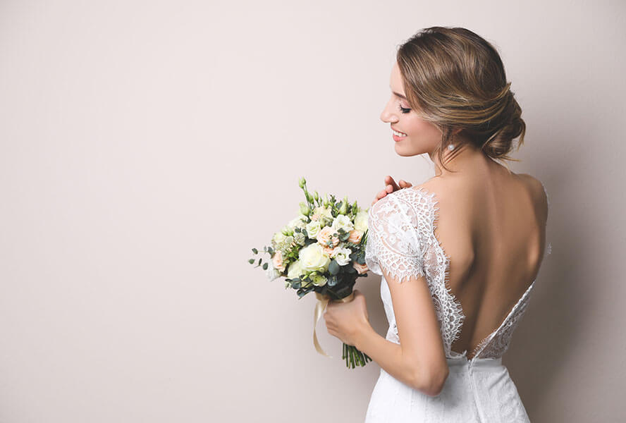 Frau im Hochzeitskleid von hinten mit hochgesteckter Brautfrisur