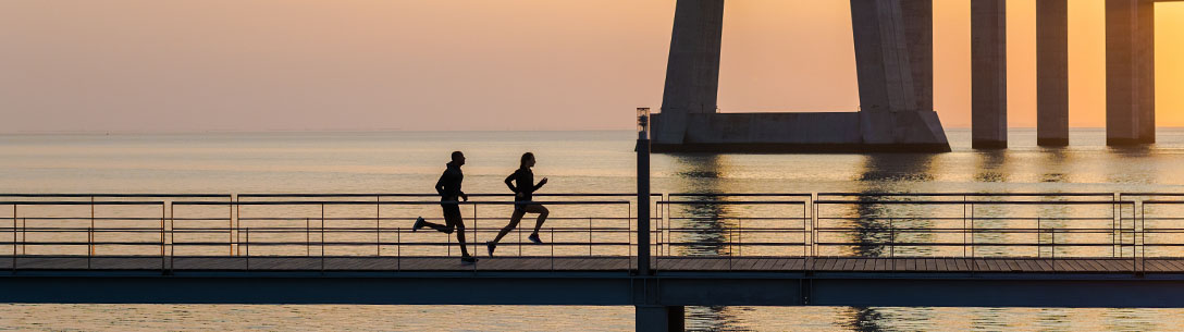Zwei Läufer joggen an Promenade