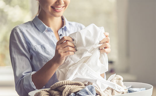 Frau mit hellblauer Bluse sortiert ihre Wäsche