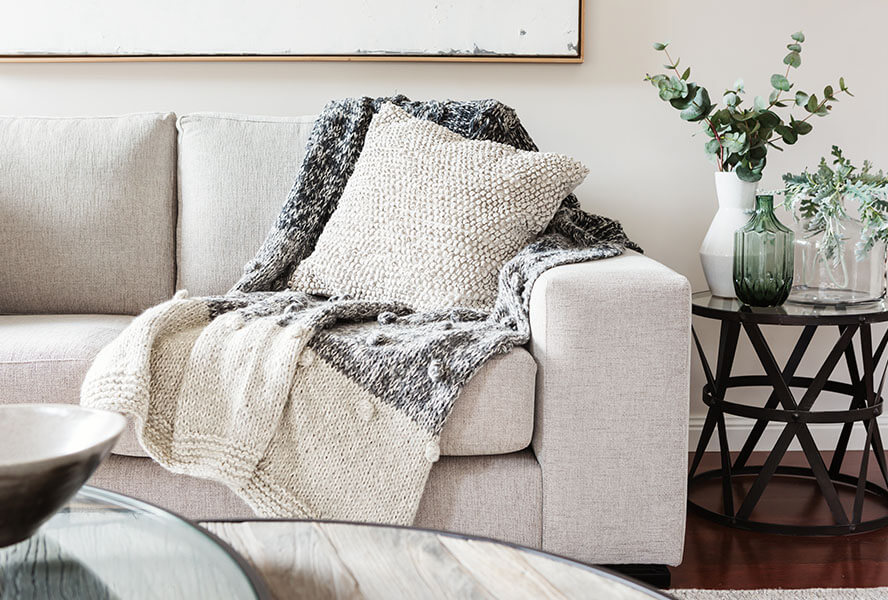 Sofa auf einem Teppich mit gemütlichen Kissen und einer Tagesdecke