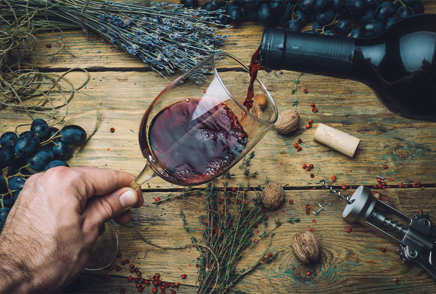 Glast Rotwein mit Weinflasche, Korkenzieher, Nüssen, Trauben und Lavendel