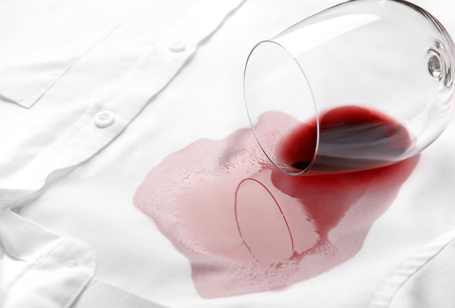 Ausgelaufenes Glas Rotwein auf einem weißen Hemd