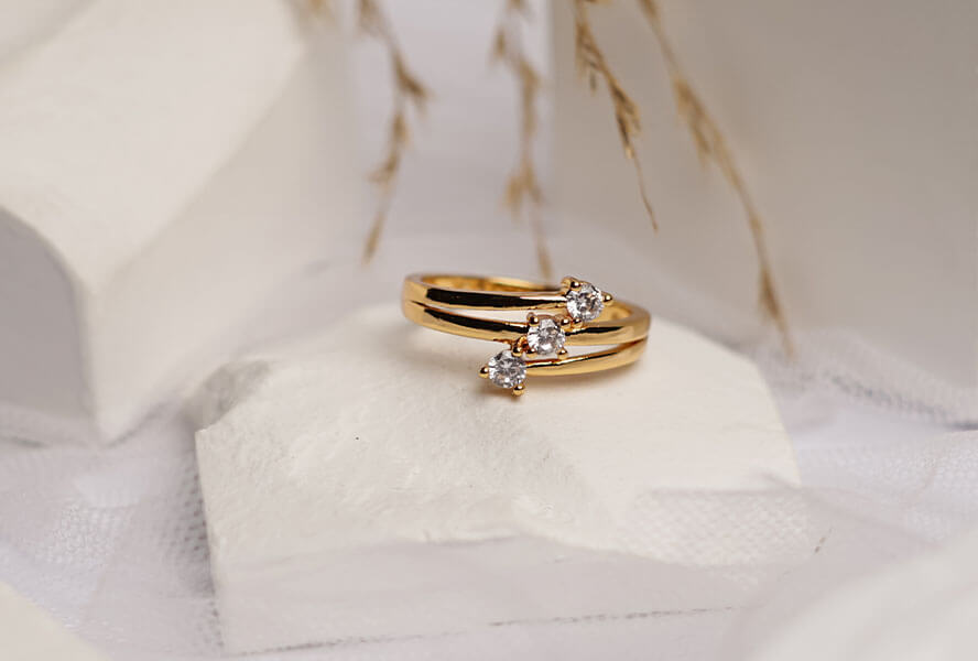 Goldener Ring mit drei Diamanten auf einem weißen Stein
