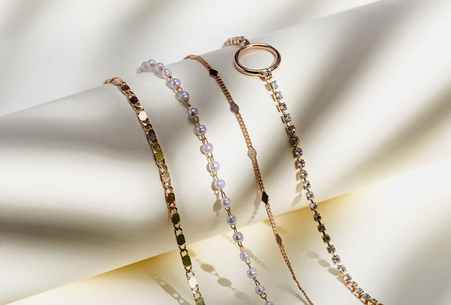 Verschiedene Armbänder aus Gold mit Perlen und Diamanten auf weissem Hintergrund
