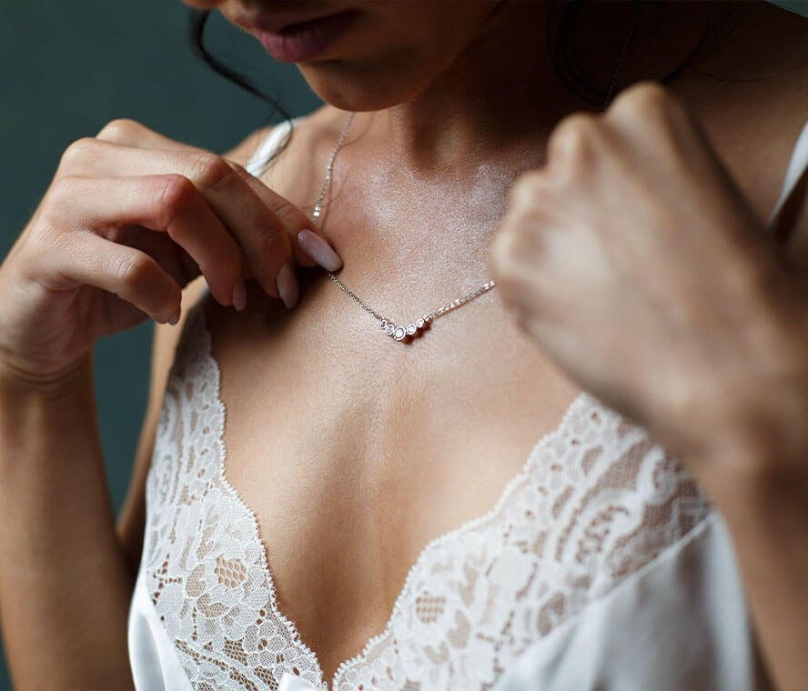 Frau legt sich eine feingliedrige Silberkette um den Hals