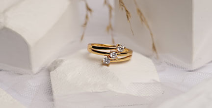 Goldener Ring mit drei Diamanten auf einem weißen Stein