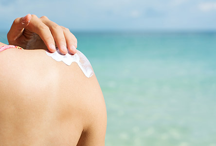 Frau im Bikini cremt sich mit Sonnencreme ein